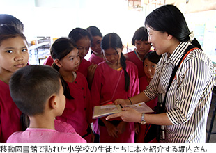 画像:移動図書館で訪れた小学校の生徒たちに本を紹介する堀内さん